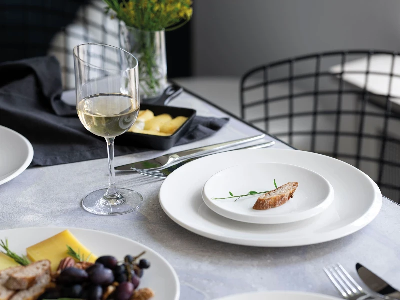 A small NewMoon plate with a slice of baguette on a table.