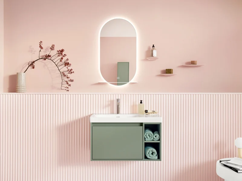 Trendy, stylishly furnished Skyla wash area in pastel shades. The wash area in this stylishly furnished bathroom is shown in a frontal view and consists of a vanity with matching base cabinet and chrome faucet - both from the Skyla bathroom collection - as well as an oval mirror from the More To See Lite+ collection.