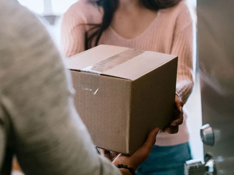Handing over a box A person hands a box to another person in a doorway.