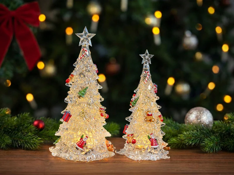 Deux guirlandes lumineuses de Noël sont posées sur un socle en bois ; à l'arrière-plan, on aperçoit un sapin de Noël et des décorations de Noël.