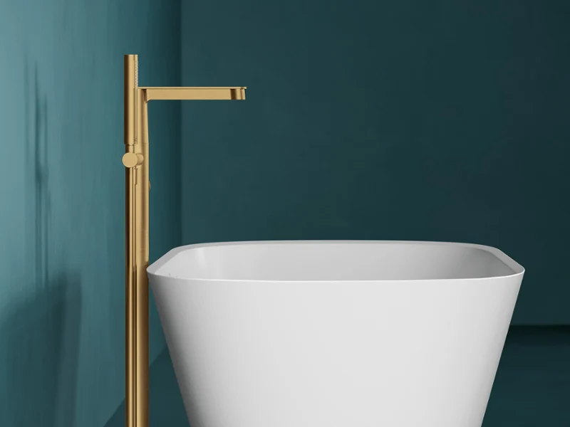 A blue-green bathroom with a modern freestanding white bath from the Theano collection and a floor-mounted gold tap from the Conum collection by Villeroy & Boch.