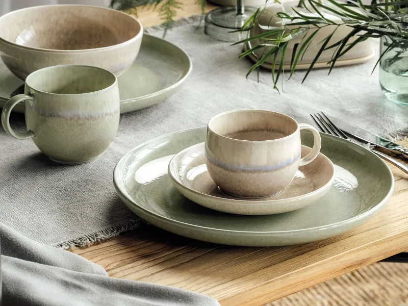 Rustic table decoration with Perlemor plates and cups in subtle earthy colours on a wooden table.