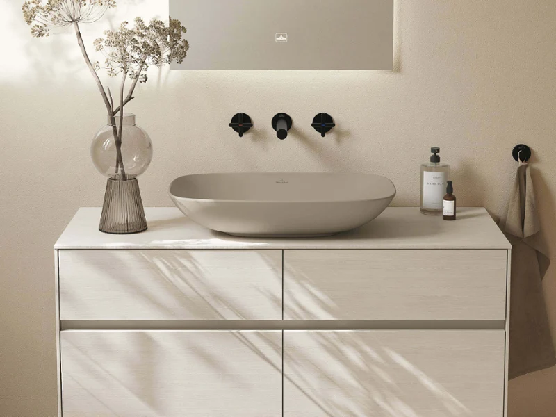 Salle de bain Collaro entièrement beige et sereine avec élégante vasque à poser, finitions mates et lumière naturelle douce. Les tons et textures naturels créent une harmonie calme et minimaliste.