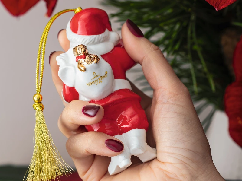 Close-up of a decorated Christmas tree with a Santa Claus ornament from Villeroy & Boch between the green branches, illuminated by small white lights.