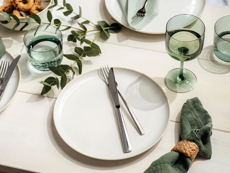 Des assiettes plates Crafted Cotton avec des verres like Glas et des couverts de table Piemont de Villeroy & Boch, le tout décoré avec des branches d’eucalyptus.