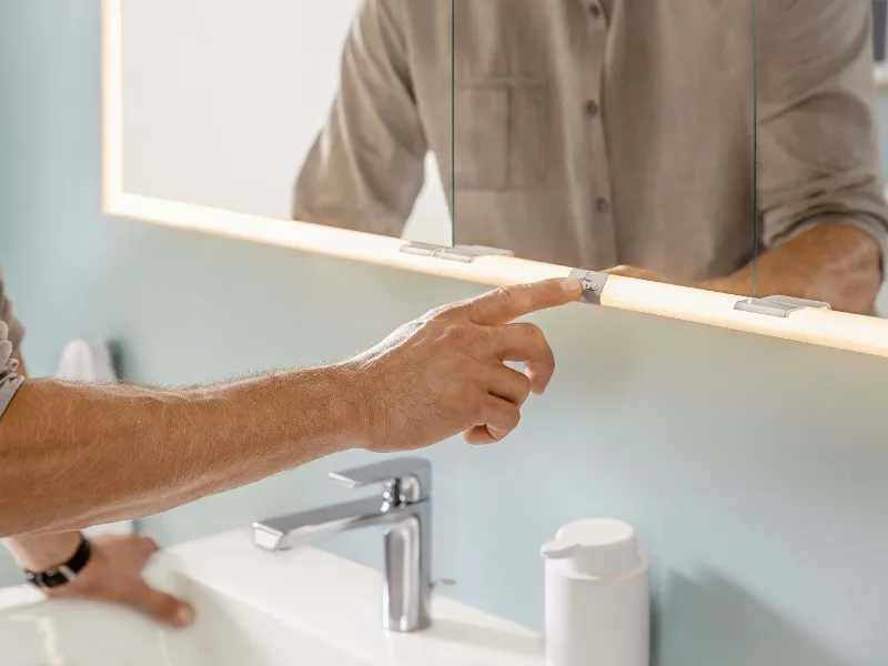 Un homme appuyant sur le bouton marche du miroir lumineux Subway 3.0 dans une salle de bains.