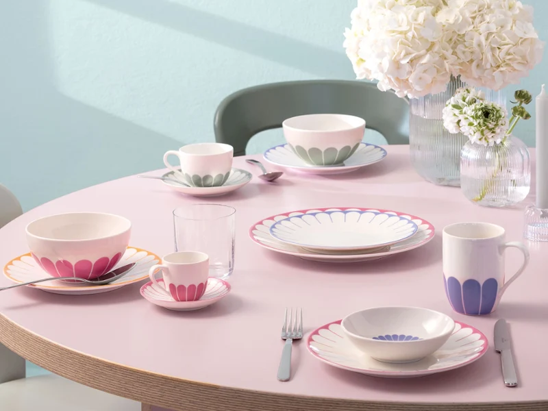 A round table setting with plates, mugs, cups, cutlery, glasses, and white flower vases from Villeroy & Boch Fleur.