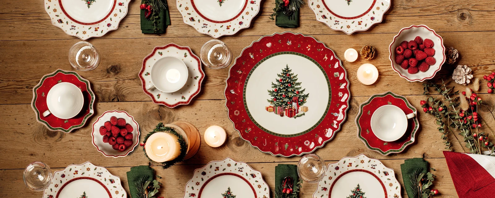 Une table de Noël avec des assiettes Toy’s Delight rouges et vertes et des serviettes Villeroy & Boch.