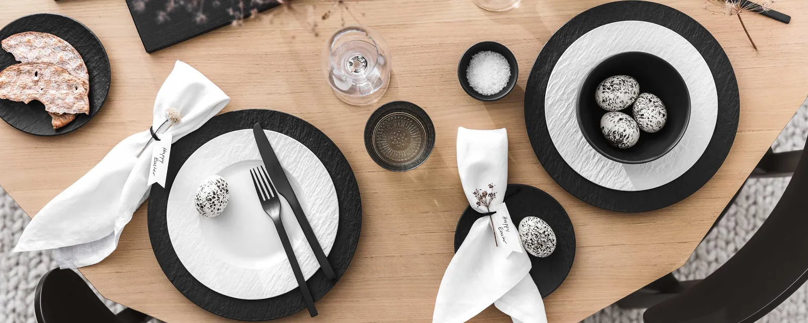 Une table de salle à manger moderne avec de la vaisselle et des couverts de table noirs et blancs de la collection Manufacture ainsi qu’une décoration de Pâques minimaliste.