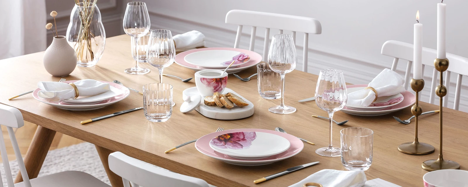 An elegant dining table with modern Rose Garden dinnerware, decorative candles and a Rose Garden vase with pampas grass.