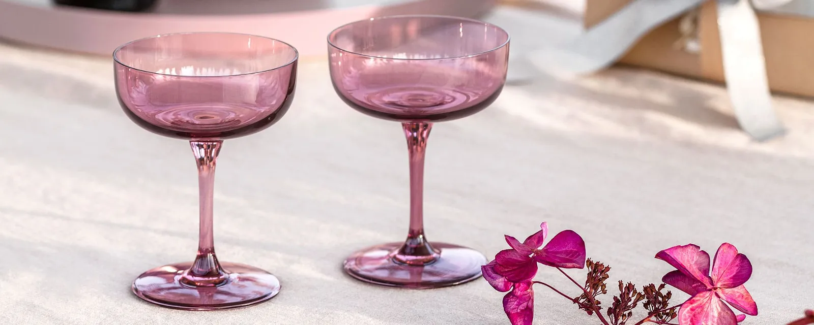 Two wine glasses from like. by Villeroy & Boch on a table next to a bottle of champagne.