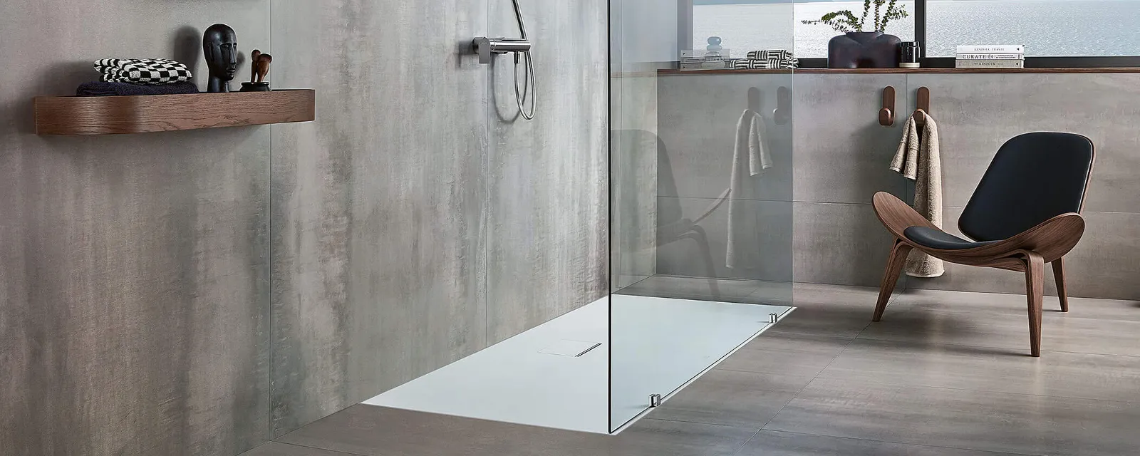 Un receveur de douche Squaro Infinity avec une chaise marron Une salle de bains grise moderne avec un receveur de douche Squaro Infinity et une chaise marron.