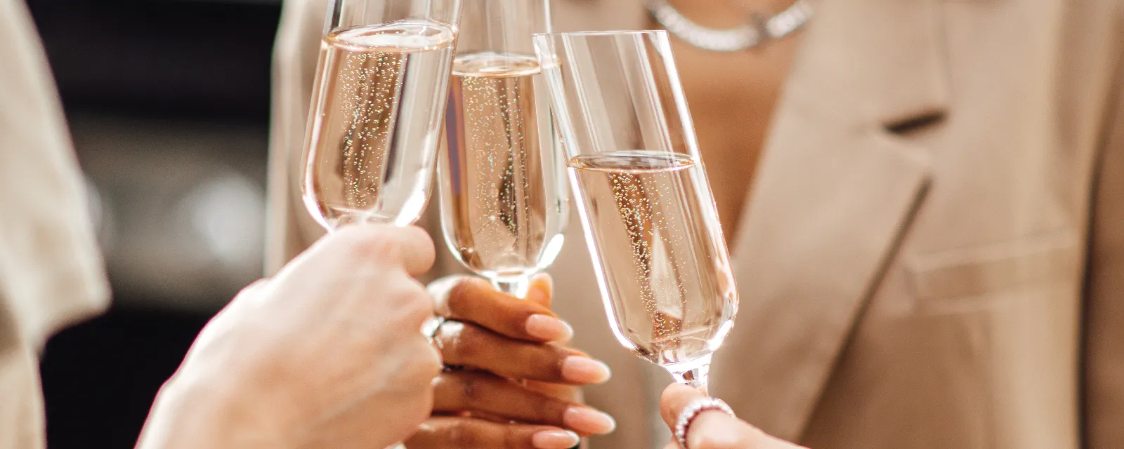 Three people dressed in neutral colours making a toast with Villeroy & Boch NewMoon champagne glasses.