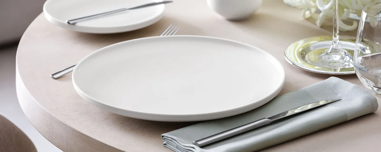 Close-up of an Afina dinner plate with subtle relief on a set table.