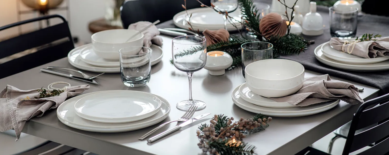 Un tavolo da pranzo apparecchiato con stoviglie, bicchieri e decorazioni della collezione Winter Glow di Villeroy & Boch.