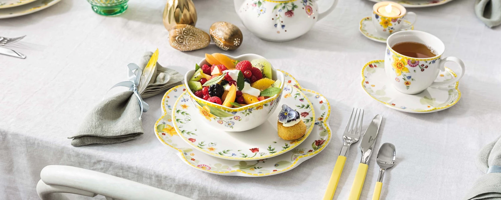 Une table de brunch de Pâques colorée, dressée avec de la vaisselle florale Spring Awakening et un saladier pleins de fruits.