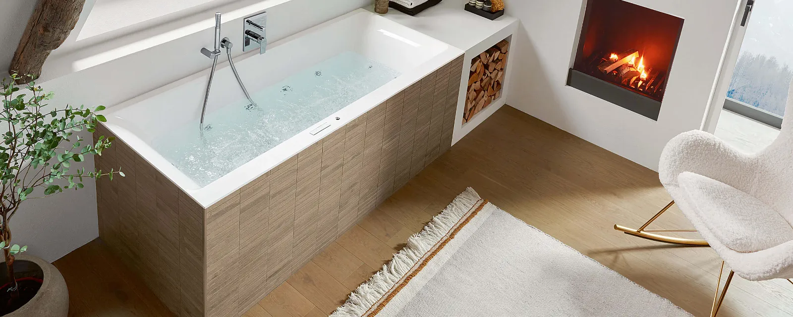 Une baignoire balnéo Subway de Villeroy & Boch Une salle de bains moderne avec une baignoire rectangulaire avec de l’eau qui s’écoule, une cheminée, une grande fenêtre avec vue sur les montagnes, des plantes en pot, des poutres en bois et une chaise sur un sol en bois dur avec un tapis.