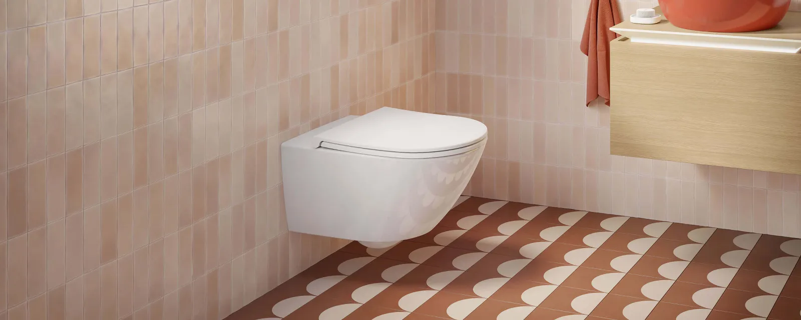 Universo TwistFlush Toilette mit orangenem Artis Waschbecken Modernes Badezimmer mit einer Universo TwistFlush Toilette, Holzwaschtisch mit orangenem Artis Waschbecken und gemusterten Bodenfliesen