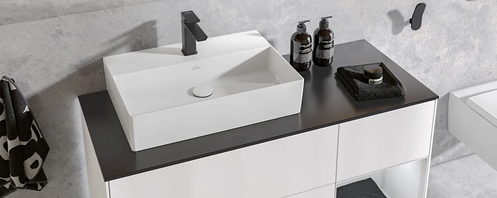 Un plan de toilette avec une vasque à poser Memento 2.0 blanche Un meuble minimaliste, noir et blanc, avec une vasque à poser rectangulaire blanche et une robinetterie chromée