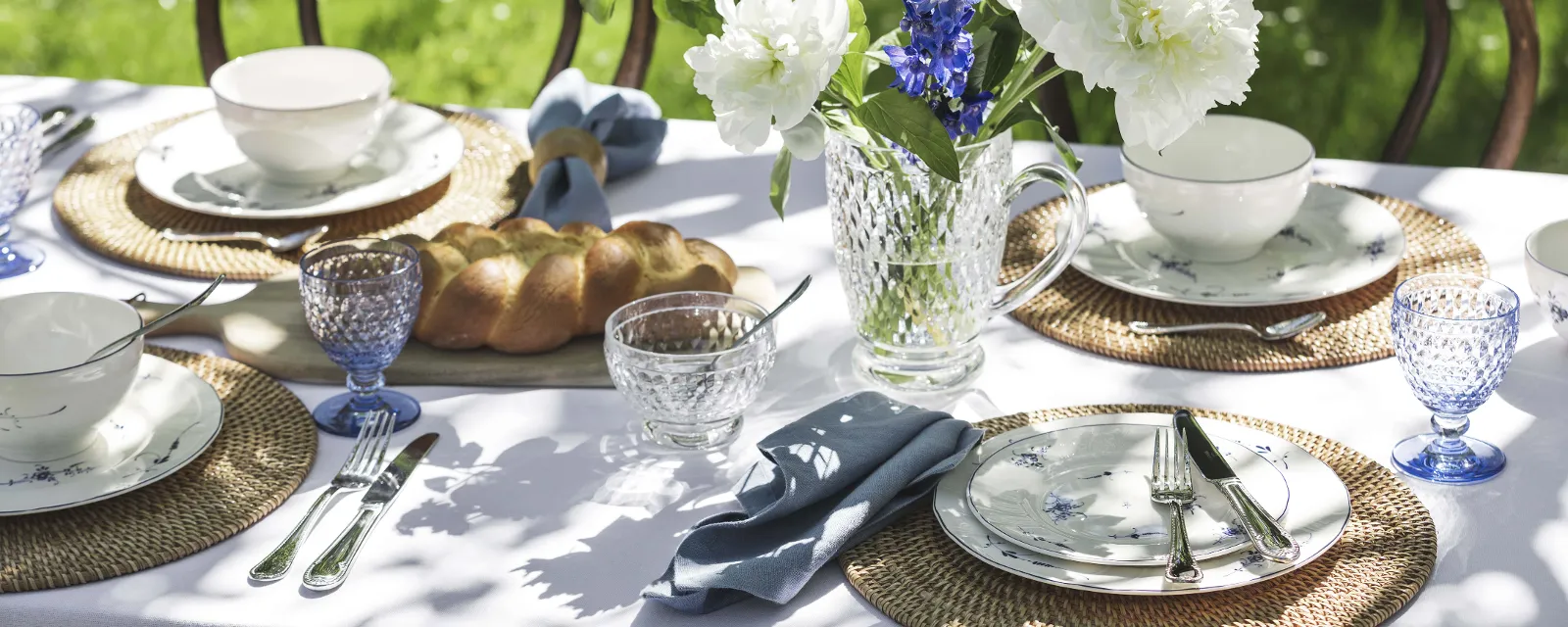 Boston glasses with Vieux Luxembourg dinnerware outdoors Elegantly set outdoor table with white and blue flower arrangements, Vieux-Luxembourg dinnerware, and Boston glasses