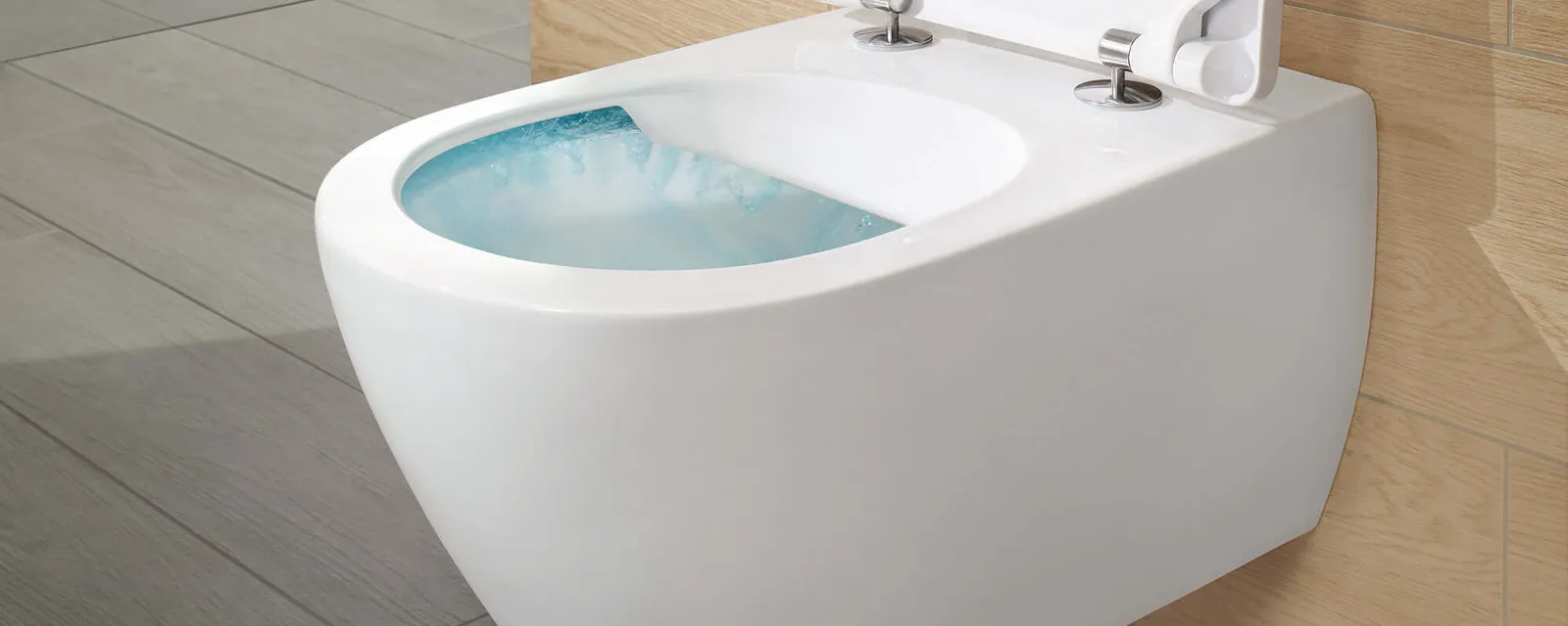 Des WC suspendus Subway 2.0 avec DirectFlush Des WC muraux modernes avec couvercle ouvert sont présentés dans une salle de bains lumineuse et minimaliste avec des touches de bois.