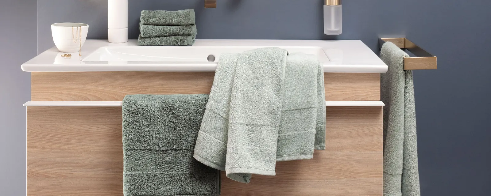 Des serviettes de toilette One vertes posées sur un meuble sous plan Un lavabo avec des serviettes de toilette vertes de la collection One de Villeroy & Boch et un miroir.
