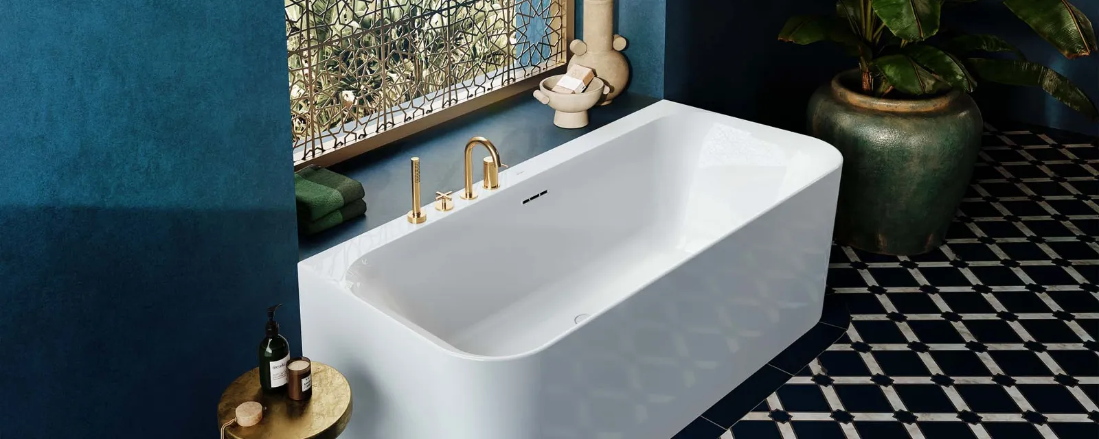 Orientalisches Badezimmer mit Loop & Friends Vorwand-Badewanne von Villeroy & Boch. Ein luxuriöses Badezimmer mit einer Vorwand-Badewanne aus der Loop & Friends Kollektion von Villeroy & Boch. Die Wanne ist weiß und hat goldene Armaturen. Das Bad ist in tiefem Blau gehalten, mit gemusterten Fliesen am Boden.