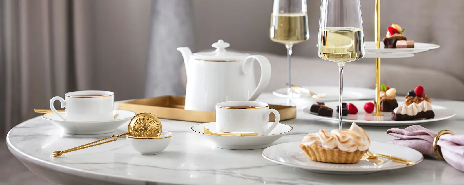 L’heure du thé à l’anglaise avec de la vaisselle Château Septfontaines et des verres MetroChic Une composition de table élégante pour le thé de l’après-midi avec des desserts et du champagne sur une table en marbre, servis sur de la vaisselle Château Septfontaines et avec des verres MetroChic.