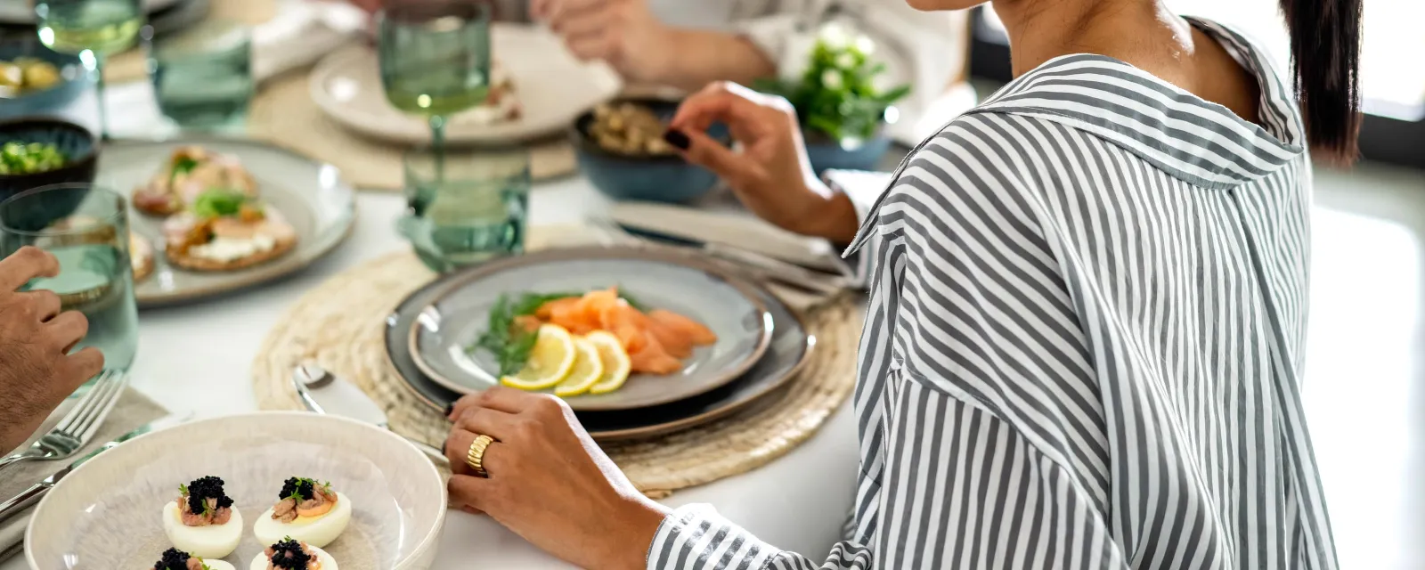 De la vaisselle Lave sur une table dressée avec des personnes Une table dressée avec de vaisselle Lave beige de like. by Villeroy & Boch avec des personnes qui mangent ensemble.
