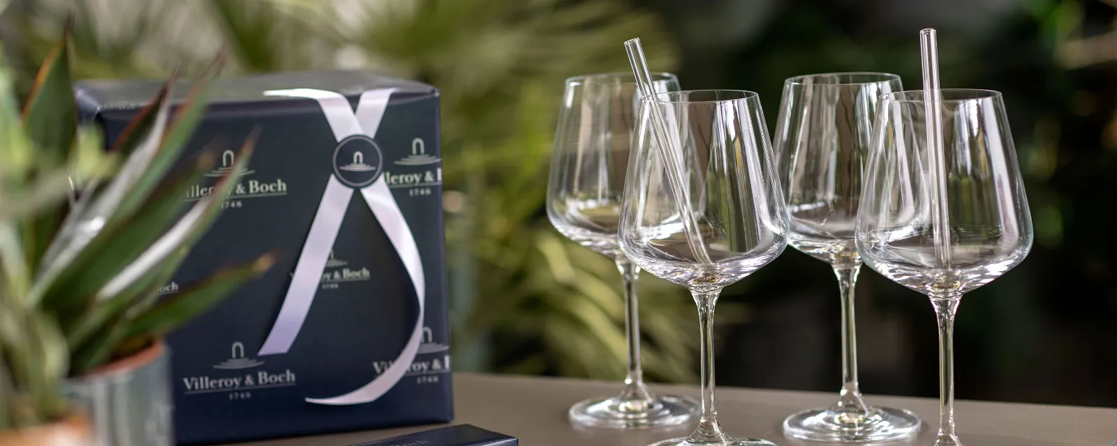 A group of Ovid wine glasses with Purismo glass straws on a table.