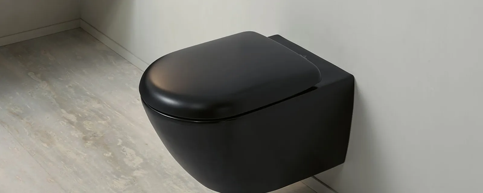 Un WC sospeso di Villeroy & Boch della collezione Antao in nero su una parete del bagno in verde delicato.