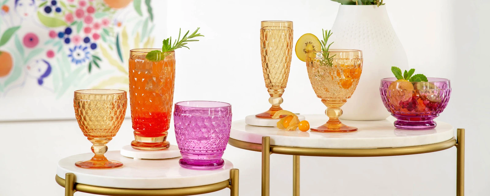 Colorful summer drinks in various Boston glasses on a chic serving table with a flower painting in the background.