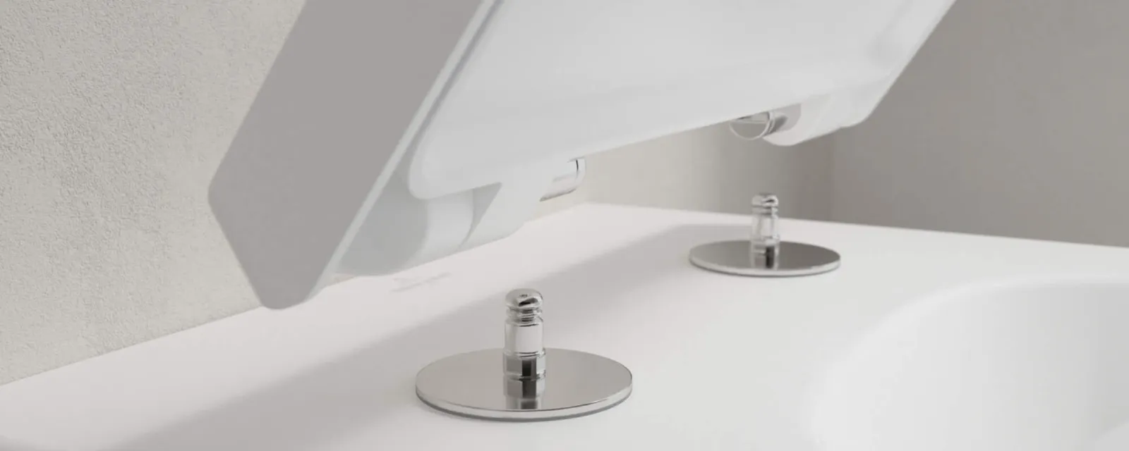 Venticello WC-Sitz der am WC befestigt wird Nahaufnahme einer weißen Toilette mit offenem Deckel, auf der die Befestigungsschrauben am Toilettensitz zu sehen sind. Der Hintergrund ist eine hellgraue Wand.