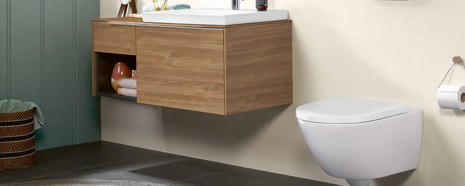 Subway 3.0 vanity washbasin on a wooden vanity unit with a mirror Modern bathroom with a round mirror above a wooden vanity unit, a floating toilet and a wall shelf with accessories and towels. On the left there is a window with sunlight.