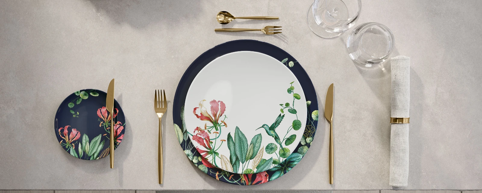 Een gedekte tafel met servies met bloemenmotief van Avarua en gouden MetroChic bestek.