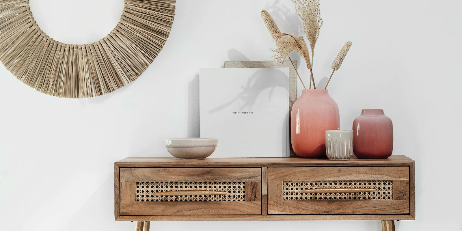 A wooden console table with Perlemor vases and a round mirror.