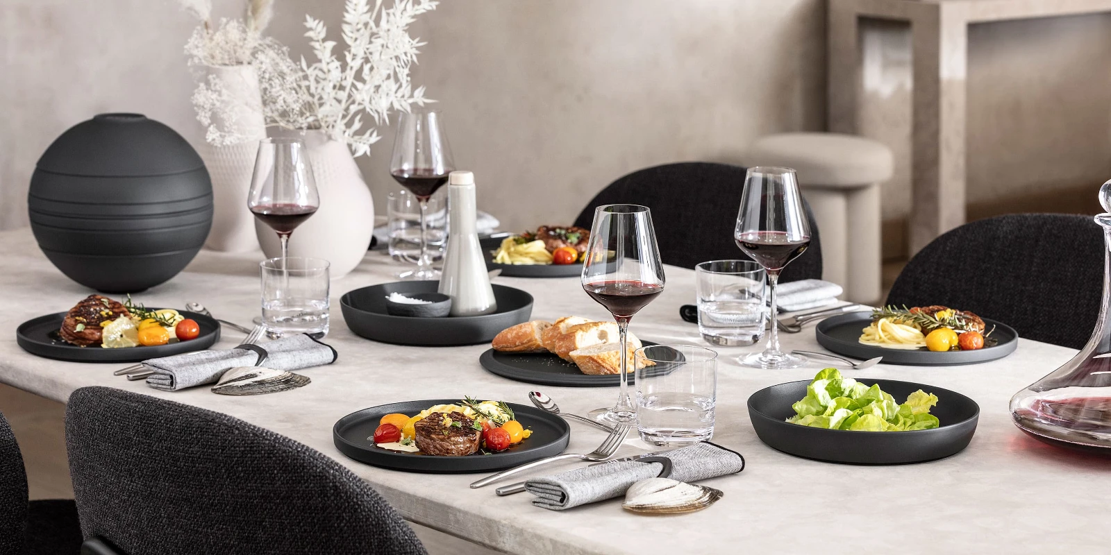 A dining table with a black La Boule being used with food as well as an assembled La Boule as decoration.