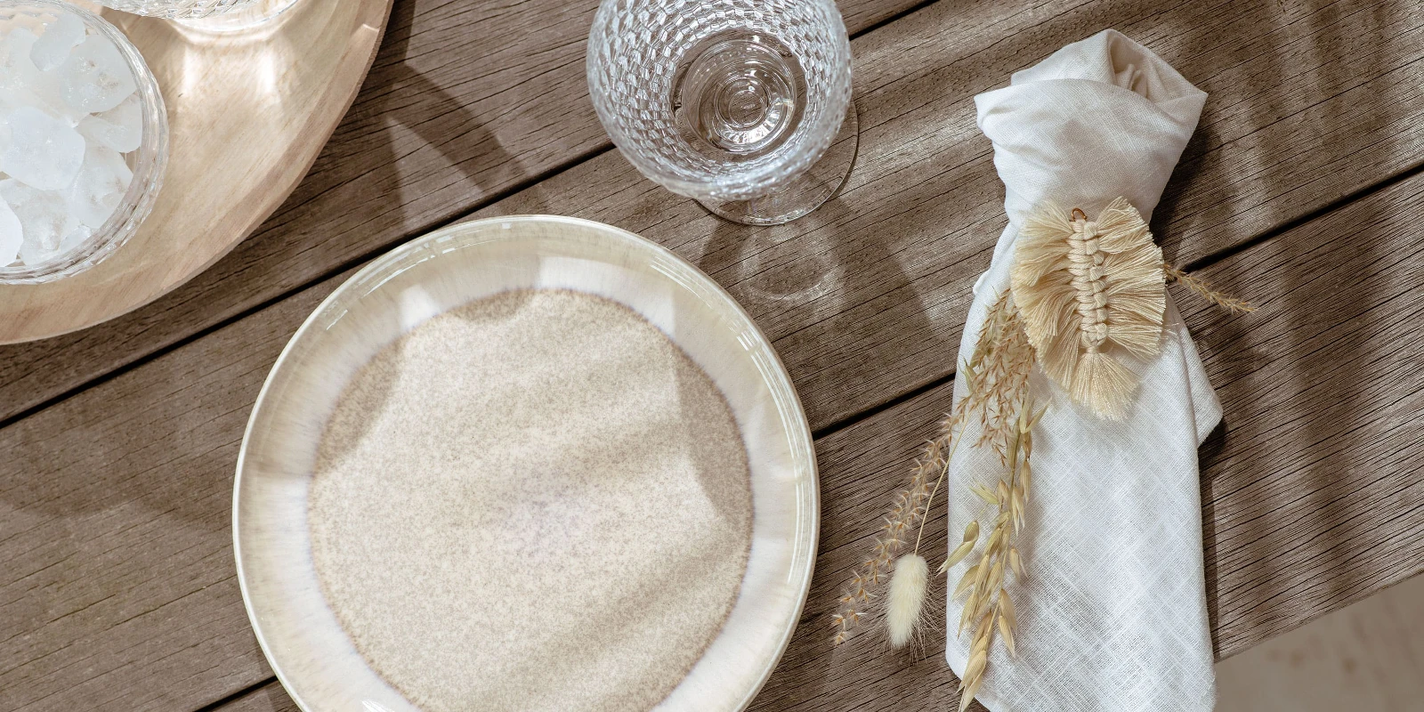 A beige Perlemor plate and a napkin on a wooden table.