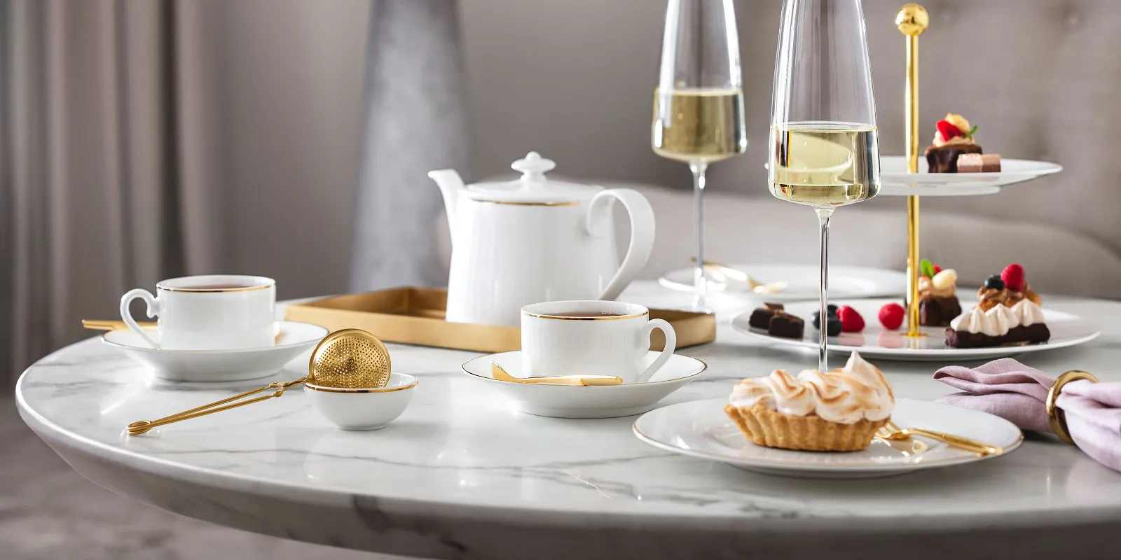 Elegant afternoon tea set-up with desserts and champagne on a marble table, served on Château Septfontaines dinnerware and MetroChic glasses.