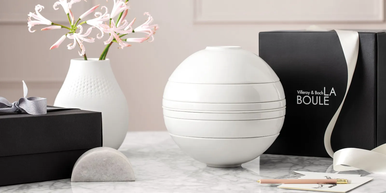 A white La Boule tableware set on a table with a black gift box behind it.