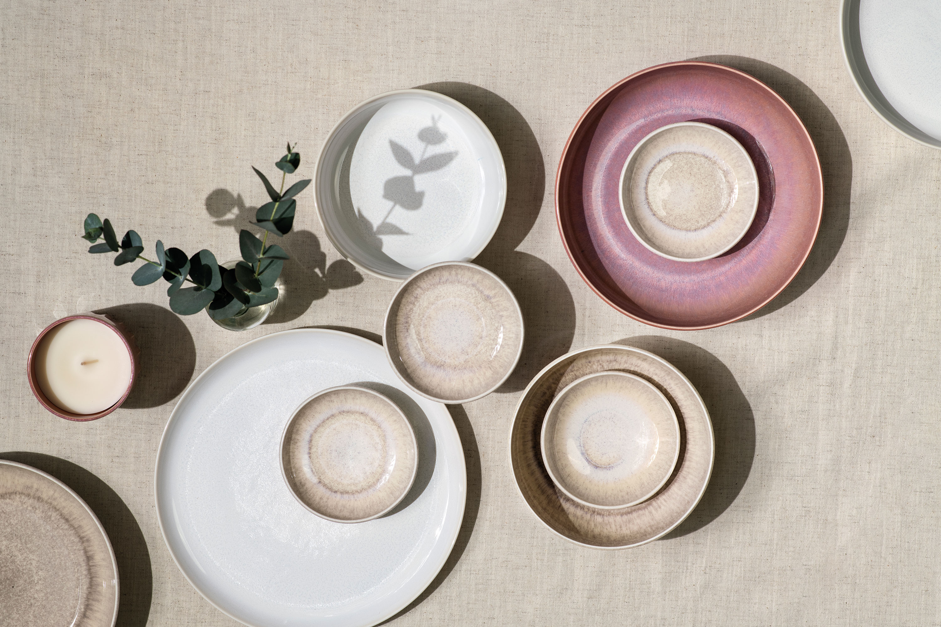 Crafted and Perlemor plates in pastel shades, arranged on a neutral textured surface.