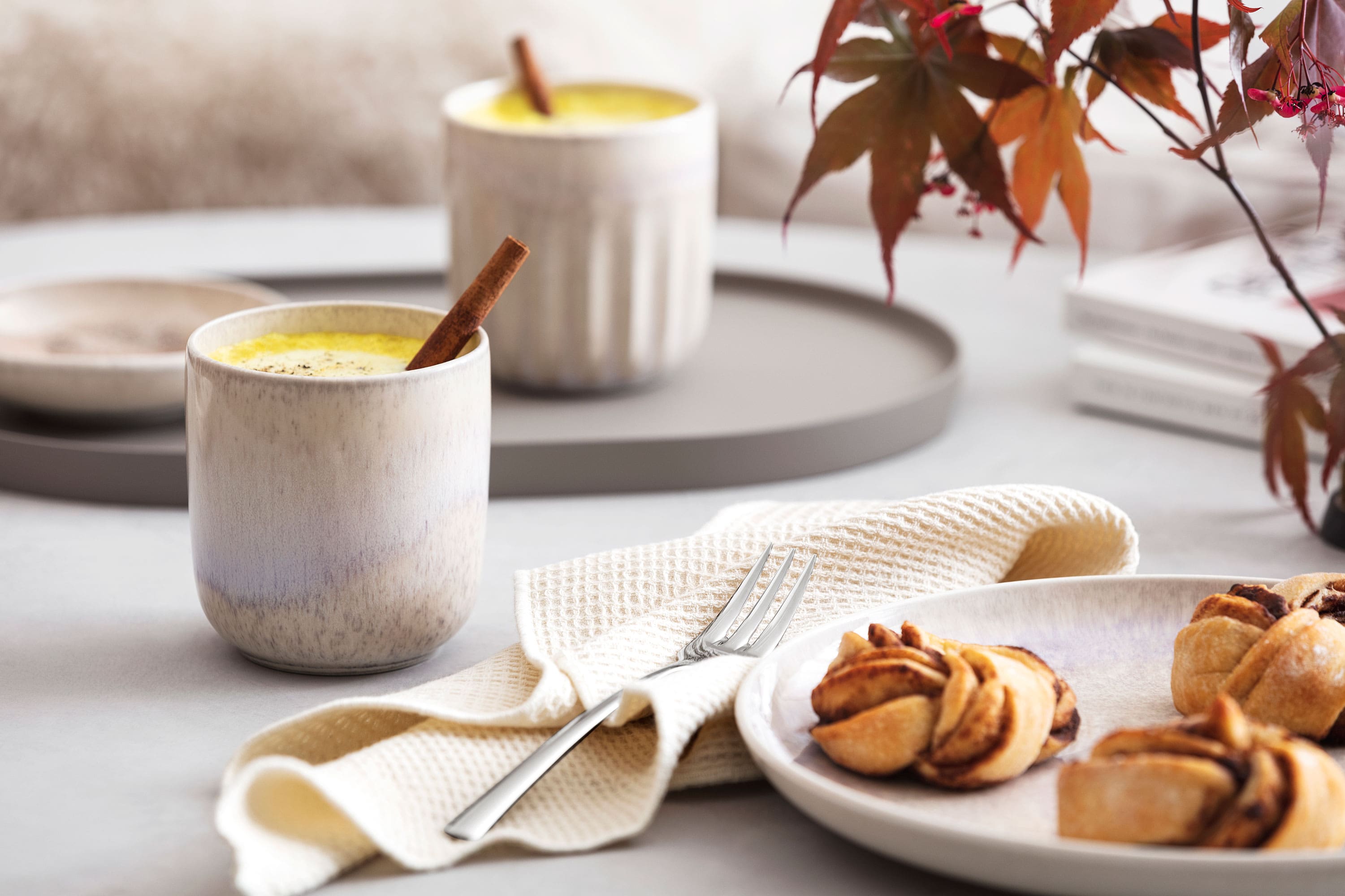 Une assiette contenant des pâtisseries et une tasse de café servie dans un mug Perlemor de like. by Villeroy & Boch sur une table.