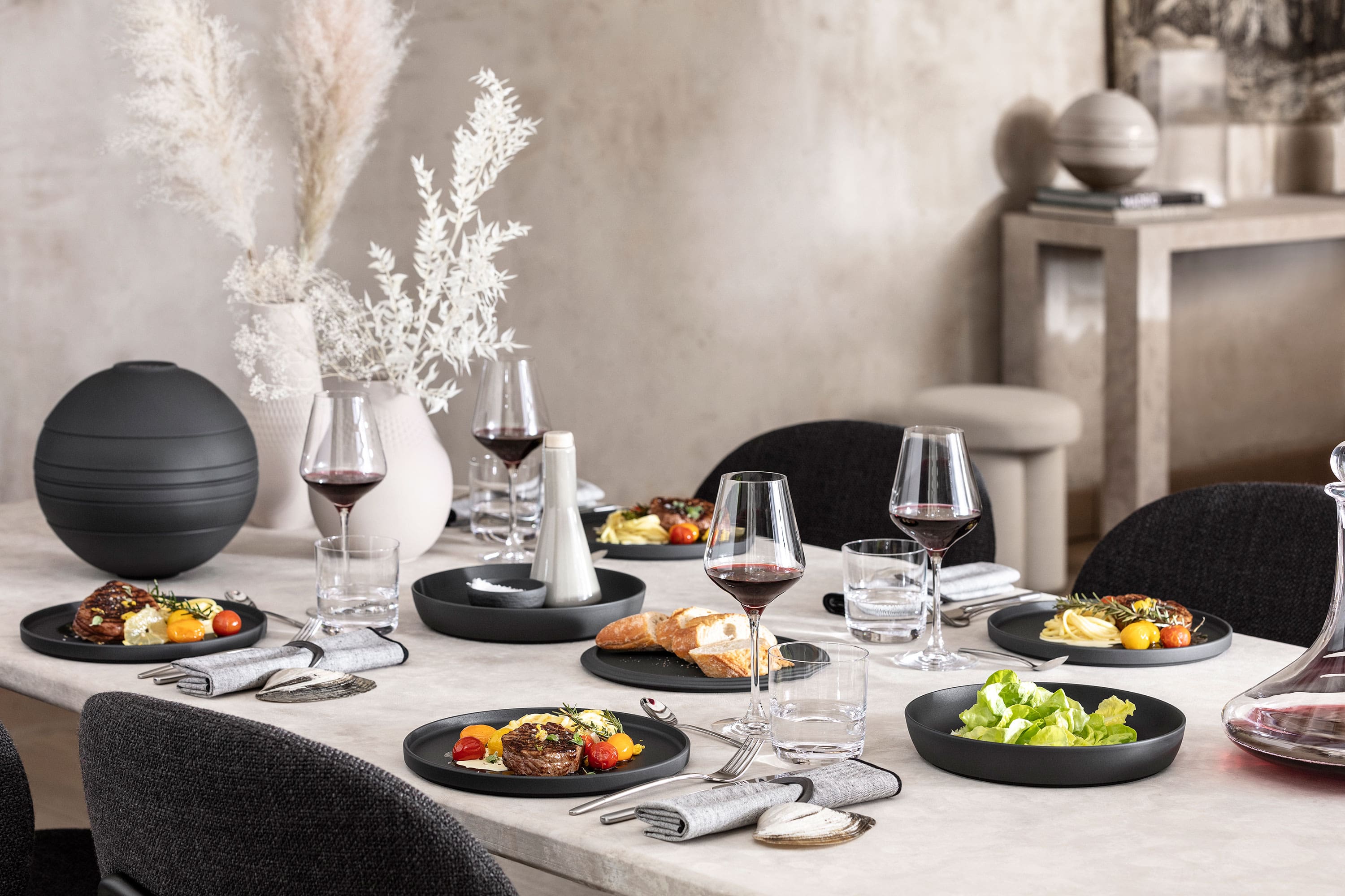 A dining table with a black La Boule being used with food as well as an assembled La Boule as decoration.