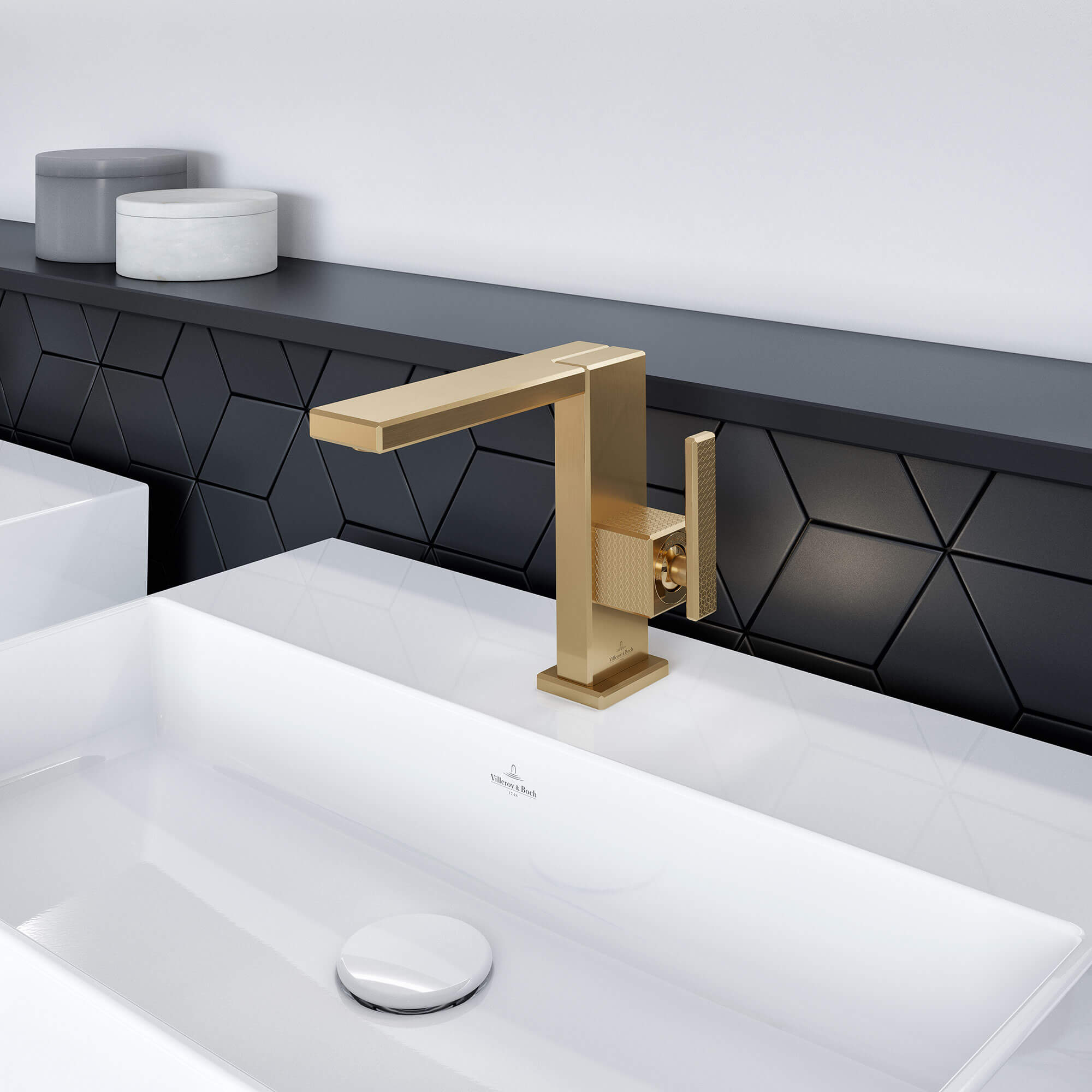 Ein moderner goldener Wasserhahn ist auf einem weißen Waschbecken mit einer schwarzen geometrischen Aufkantung in einem Badezimmer installiert.