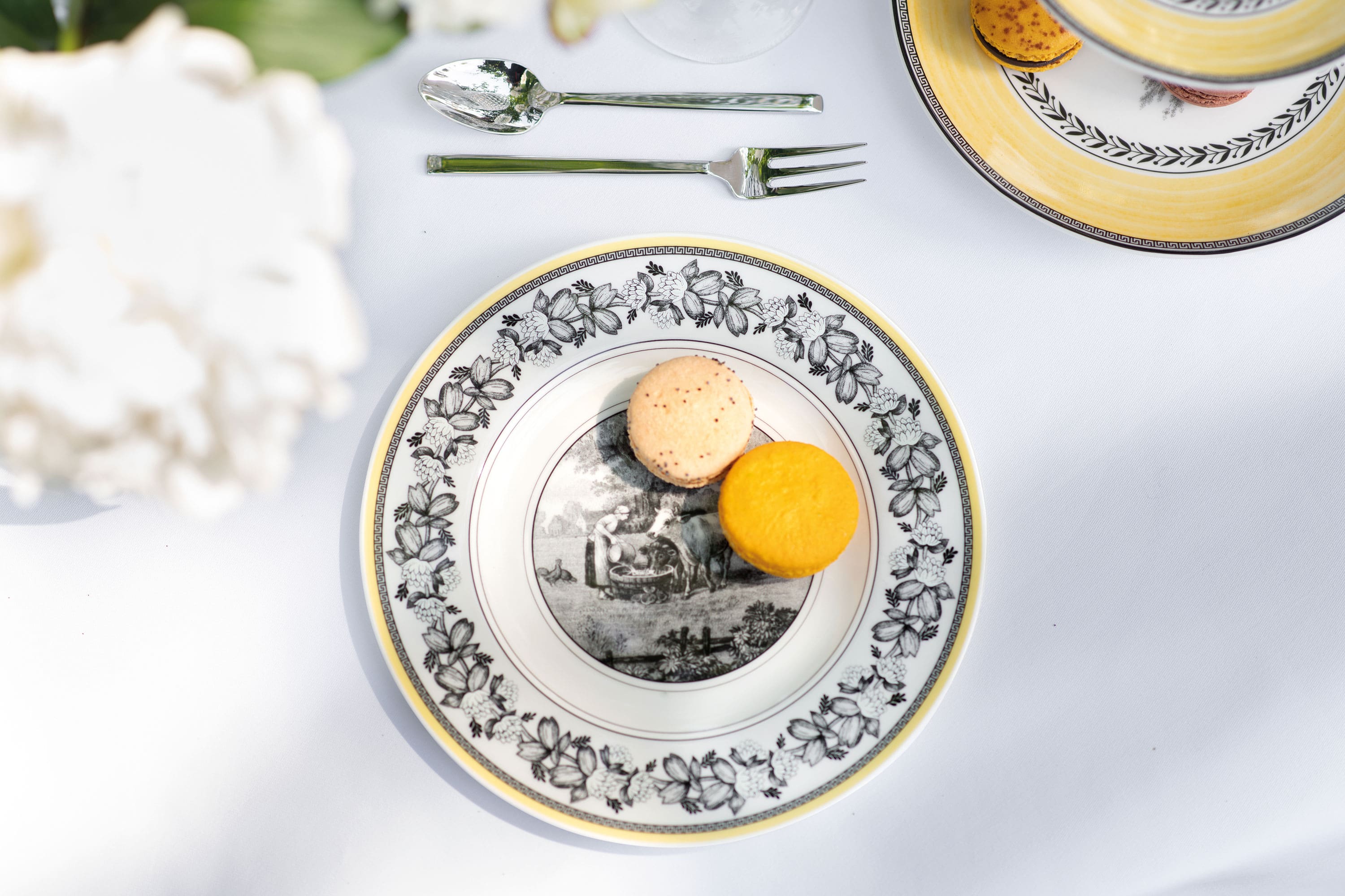 Une élégante décoration de table avec une assiette pour le petit-déjeuner décorée de la collection Audun et deux macarons.