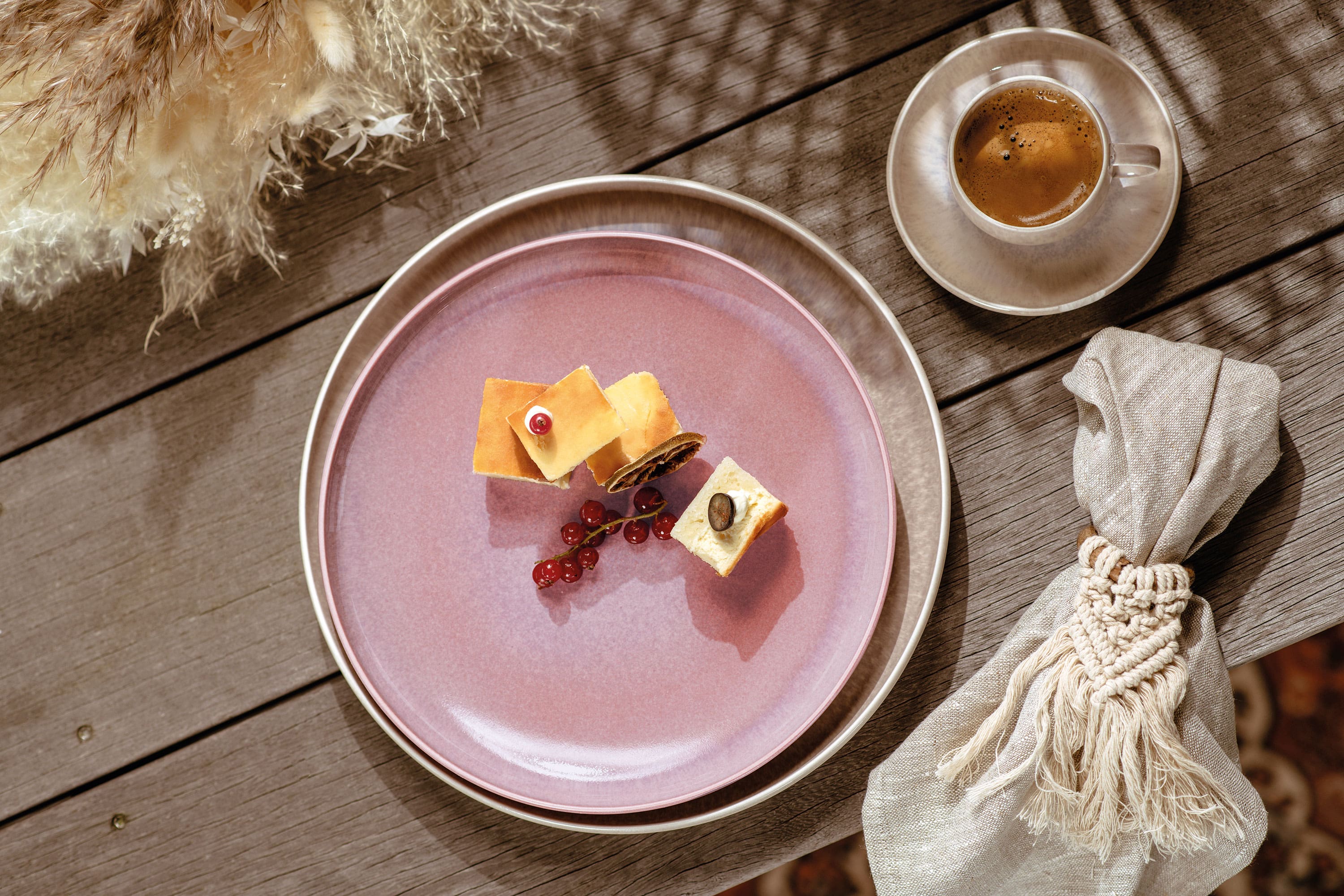 A pink Perlemor breakfast plate from like. by Villeroy & Boch with a piece of cheese and a cup of coffee.