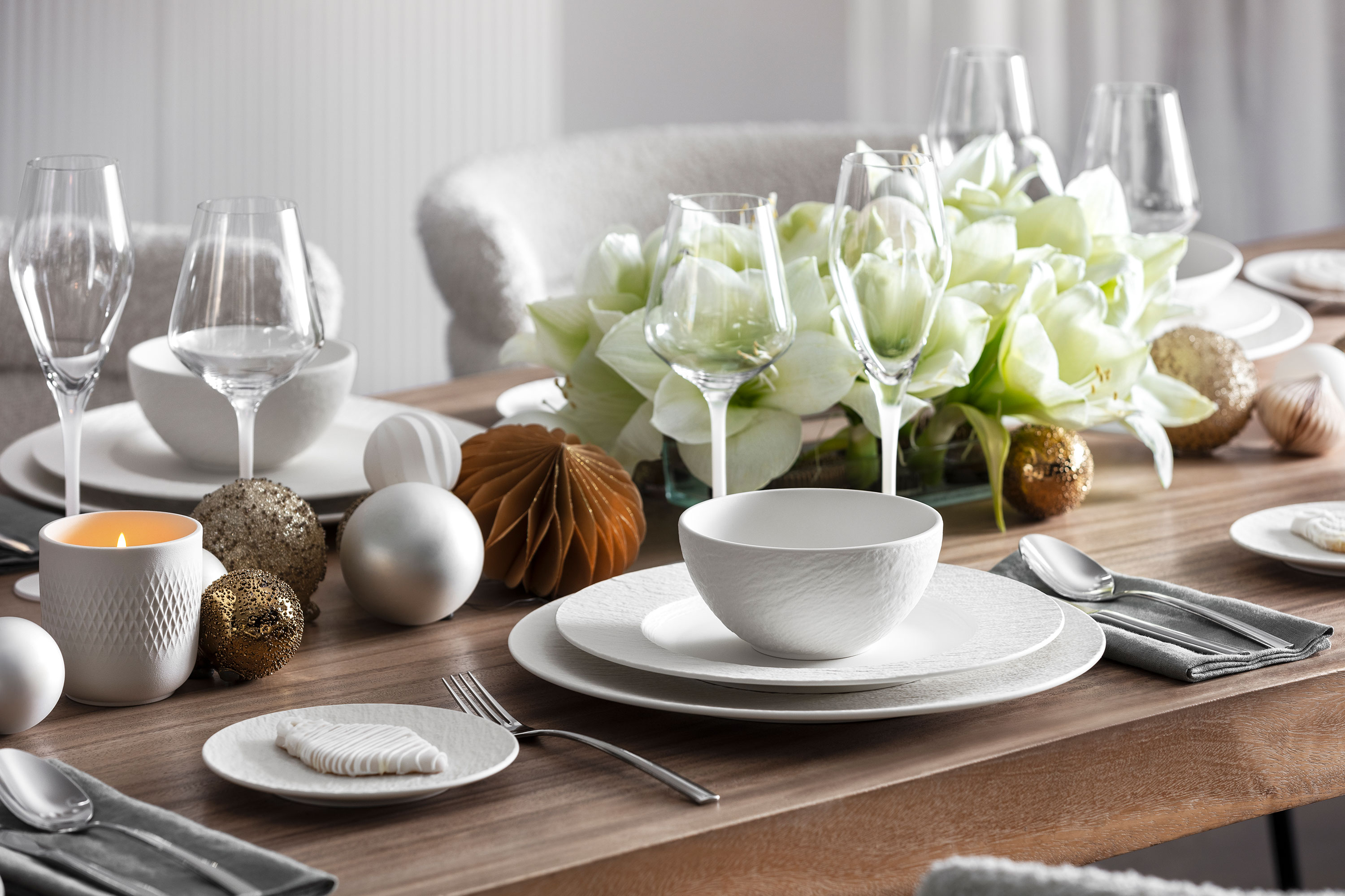 Elegant table setting with Manufacture dinnerware Elegant table setting with Manufacture dinnerware, glassware, silverware, and a centerpiece of white flowers and decorative ornaments.